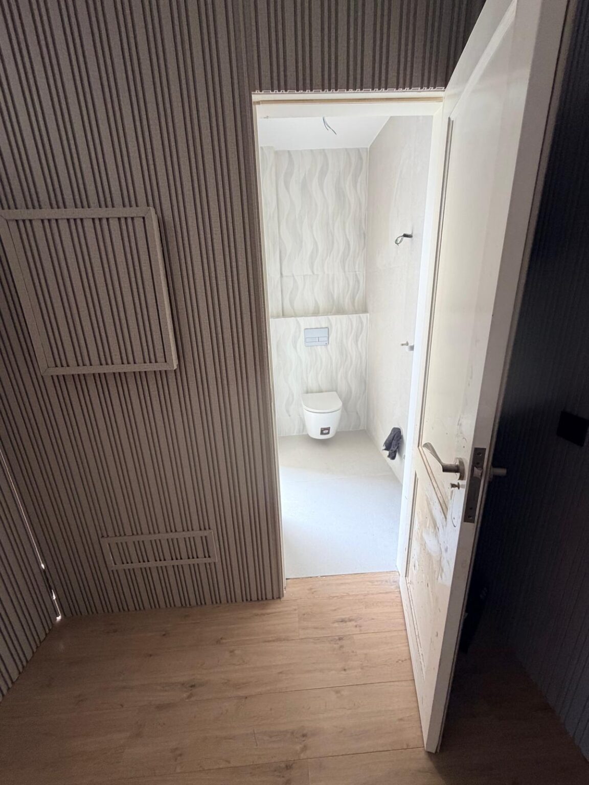 Albañil alicatando pared de baño con azulejos de gran formato en obra de reforma.